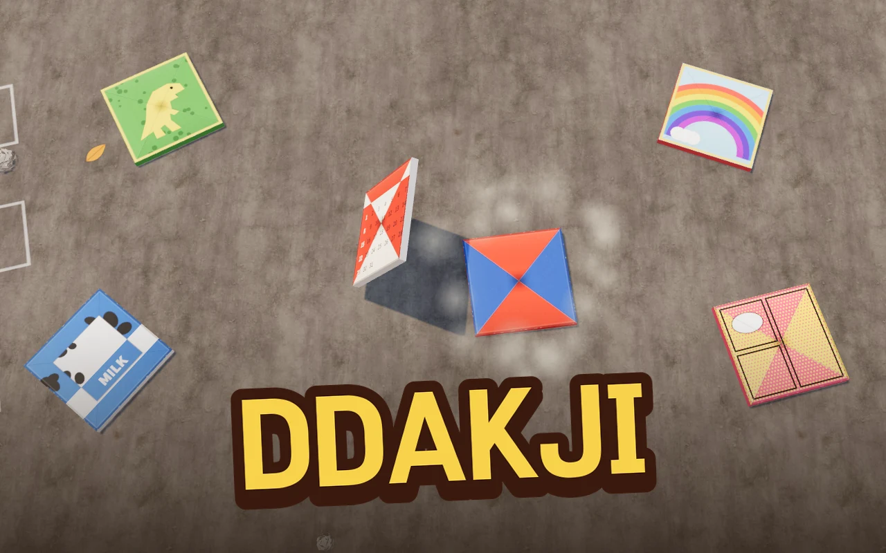 On a concrete alley floor a red paper ddakji slams down and a calendar ddakji stands up and flips over, with a dino ddakji and a rainbow ddakji nearby and the title DDAKJI across the bottom